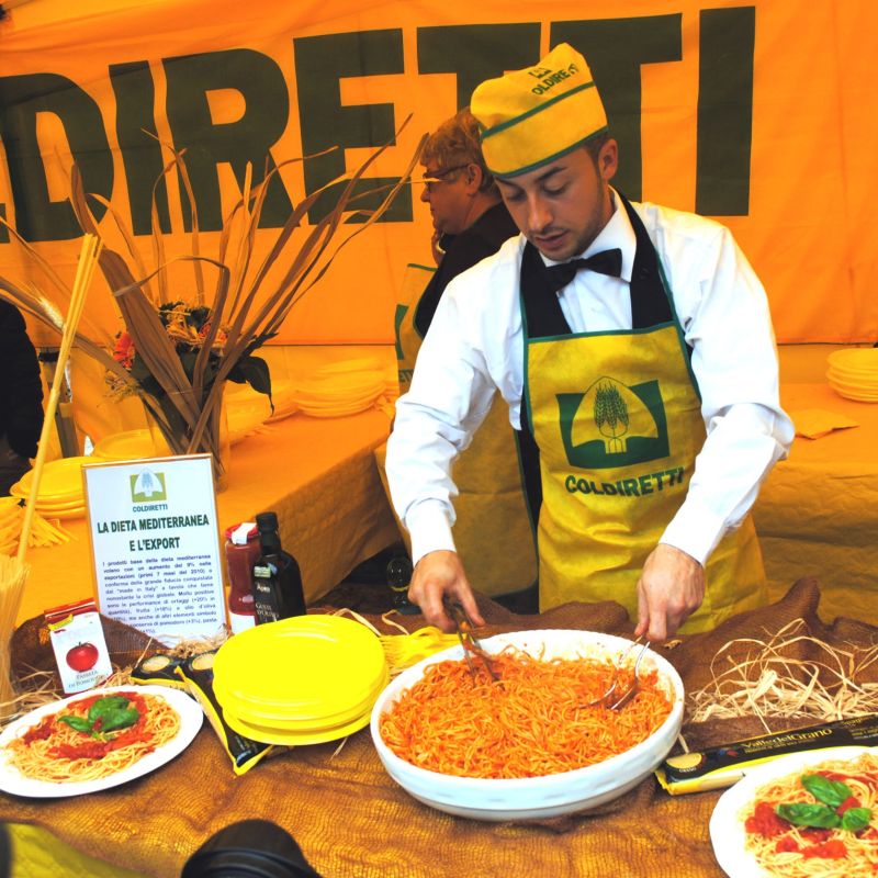 Uno chef prepara spaghetti con pomodori nello stand della Coldiretti