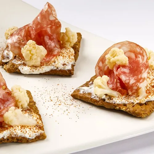 Preparazione: Dedicatevi per prima cosa alla preparazione della giardiniera: pulite il cavolfiore e ricavate da esso delle piccole cime. In una pentola portate a ebollizione l’aceto di mele con lo zenzero tagliato a losanghe e aggiungete anche le cime. Una volta raggiunto il bollore, continuate la cottura per due minuti e spegnete il fuoco. Chiudete la pentola con la pellicola e lasciate le cime in ammollo per circa un’ora.  Nel frattempo prendete il formaggio spalmabile, aggiungete l’olio extravergine d’ol