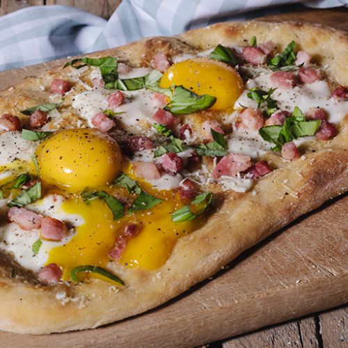 Pizza alla carbonara con uova, pancetta, scaglie di pecorino e basilico 
