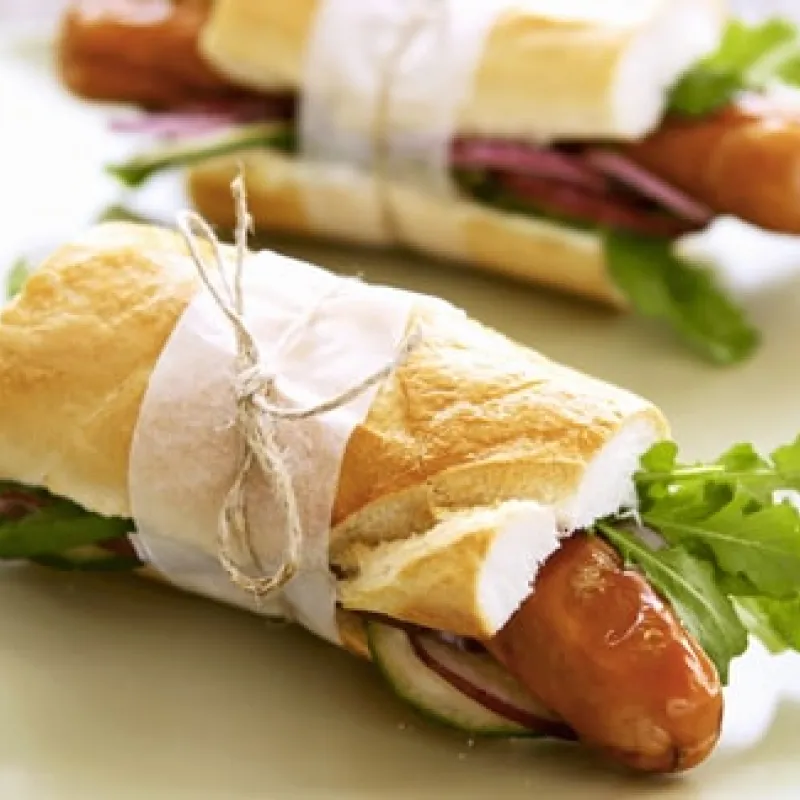 Baguette con wurstel e rucola su un piatto