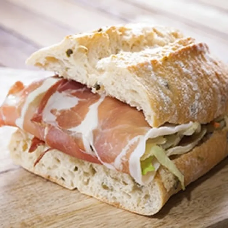 Panino farcito con prosciutto crudo su tagliere